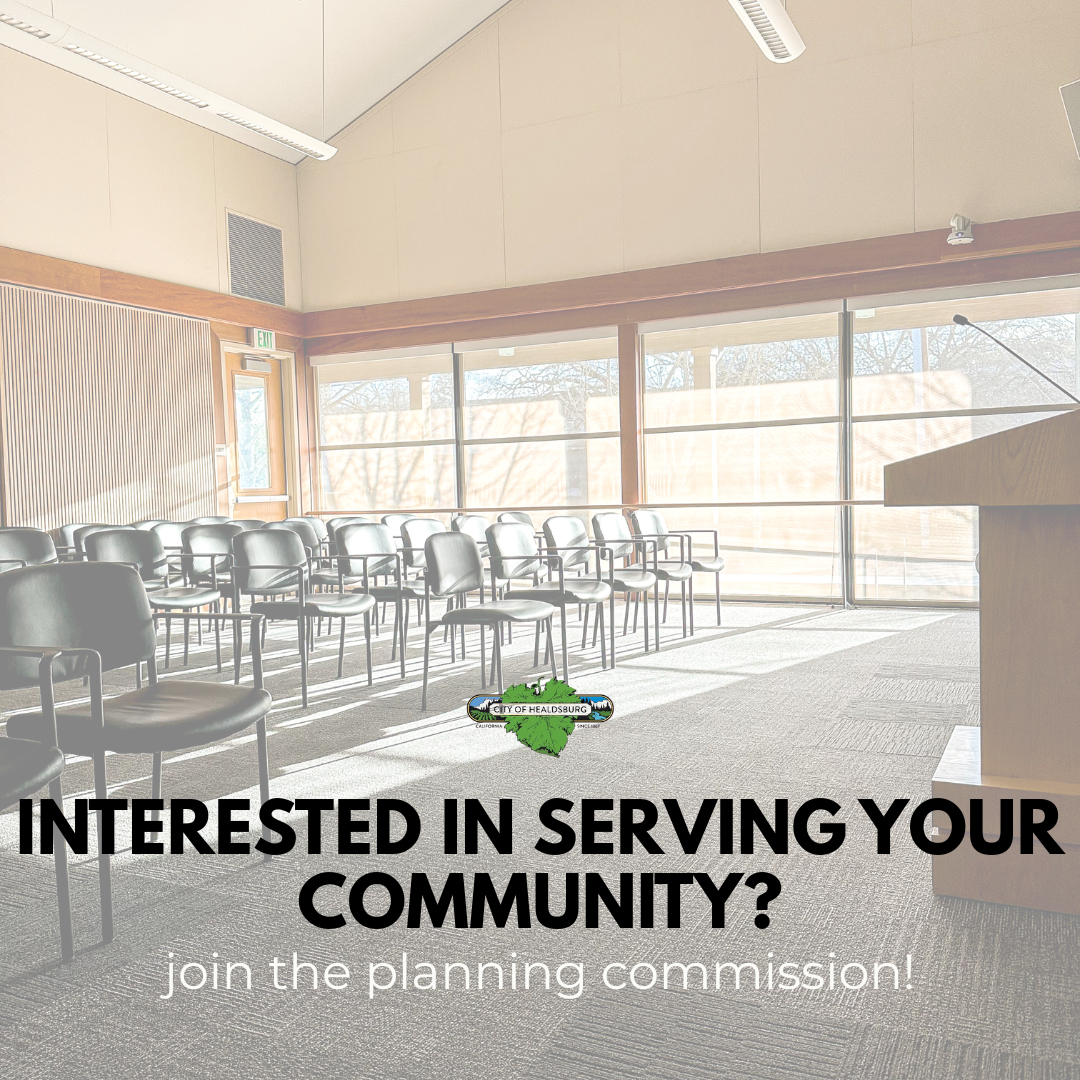 An empty Council Chamber with all black chairs, a brown podium with a microphone