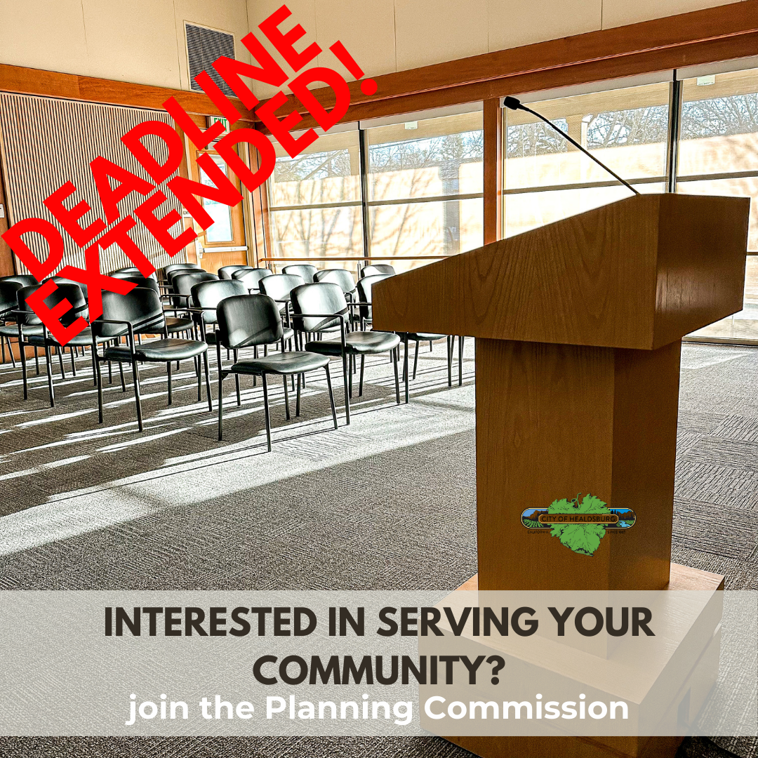 An empty Council Chamber with all black chairs, a brown podium with a microphone